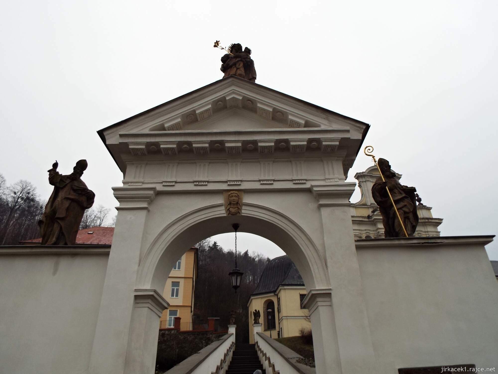 I - Fulnek - kostel Nejsvětější Trojice 07 - pískovcové postavy sv. Ambrože a Augustina, ve vrcholu tympanonu pískovcová socha sv. Josefa s Ježíškem v náručí